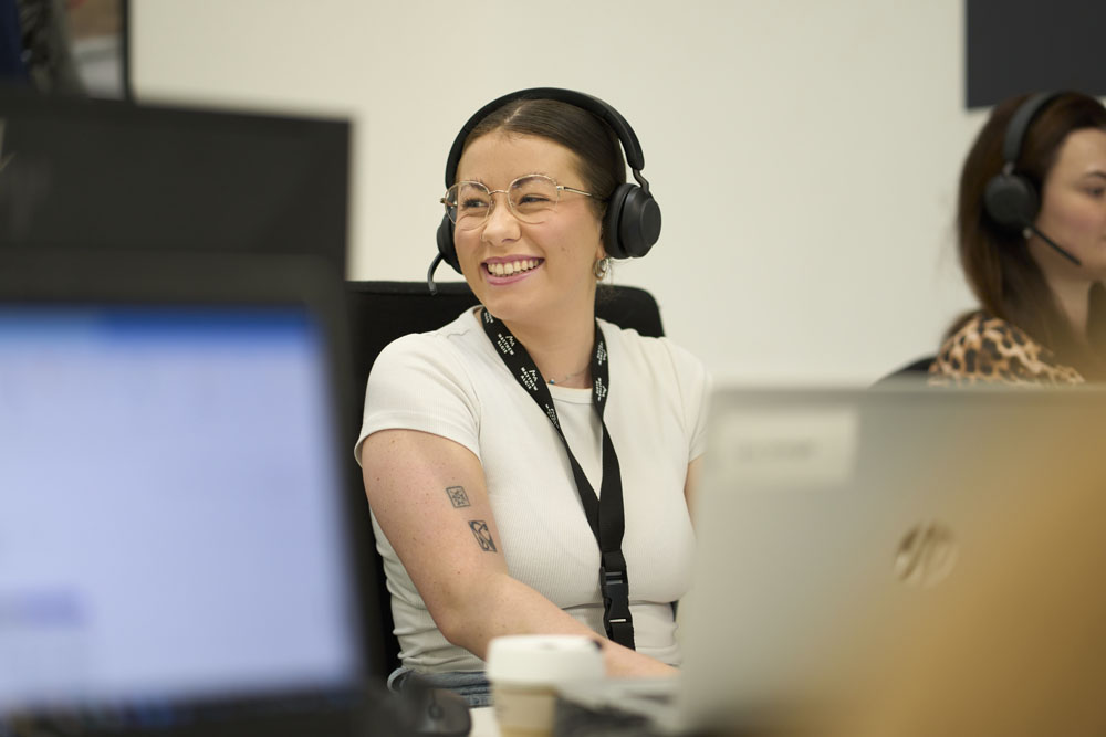 Happy young person on a phone headset in the Matthew Algie call centre