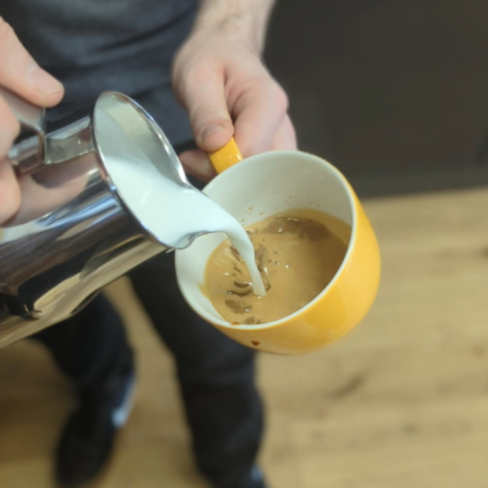 Pouring latte milk into cup